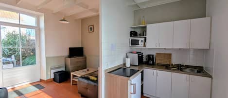 A compact kitchen with white cabinets, a microwave, a toaster, and a small refrigerator.