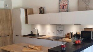 A modern kitchen with a wooden countertop, a sink, and a microwave.