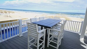 Una terraza de madera con una mesa y sillas con vistas a la playa.