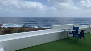 A terrace with a table and chairs overlooking the sea. - Laranjinha Rooms (Paul)