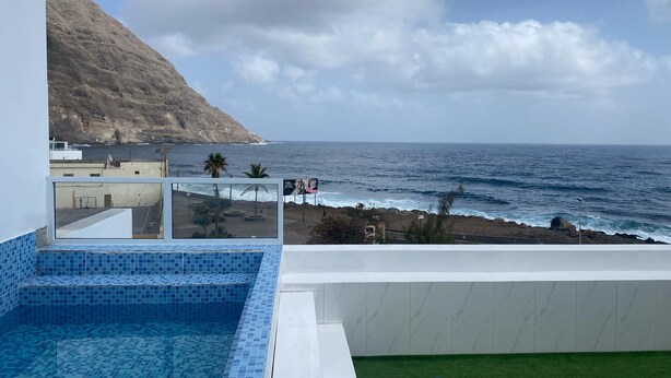 A rooftop pool with a view of the ocean and a rocky hillside. - Laranjinha Rooms (Paul)