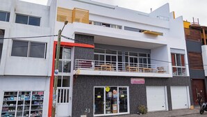 A two-story building with a ground-floor retail space and a second-floor residential unit. - Laranjinha Rooms (Paul)