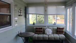 Una habitación acogedora con un banco acolchado, una pequeña mesa redonda y una ventana con persianas.