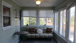 Una habitación con sofá, una mesa y un ventilador de techo.