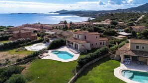 Um complexo de villas à beira-mar, com vários edifícios, piscina e vista para o mar.