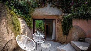Fachada de piedra con entrada de puerta de cristal, sillas de mimbre blanco y una escalera de piedra.
