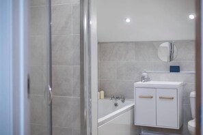 A modern bathroom with a glass shower enclosure, a white sink with a mirror, and a bathtub.