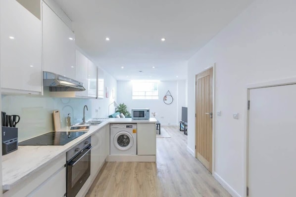 A compact kitchen with a washing machine, a microwave, and a sink.