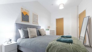 A bedroom with a grey bed, white nightstand, and a wooden door. - Sleeps 4 | Perfect for Contractors w/ Free Wi-Fi (Newark-on-Trent)