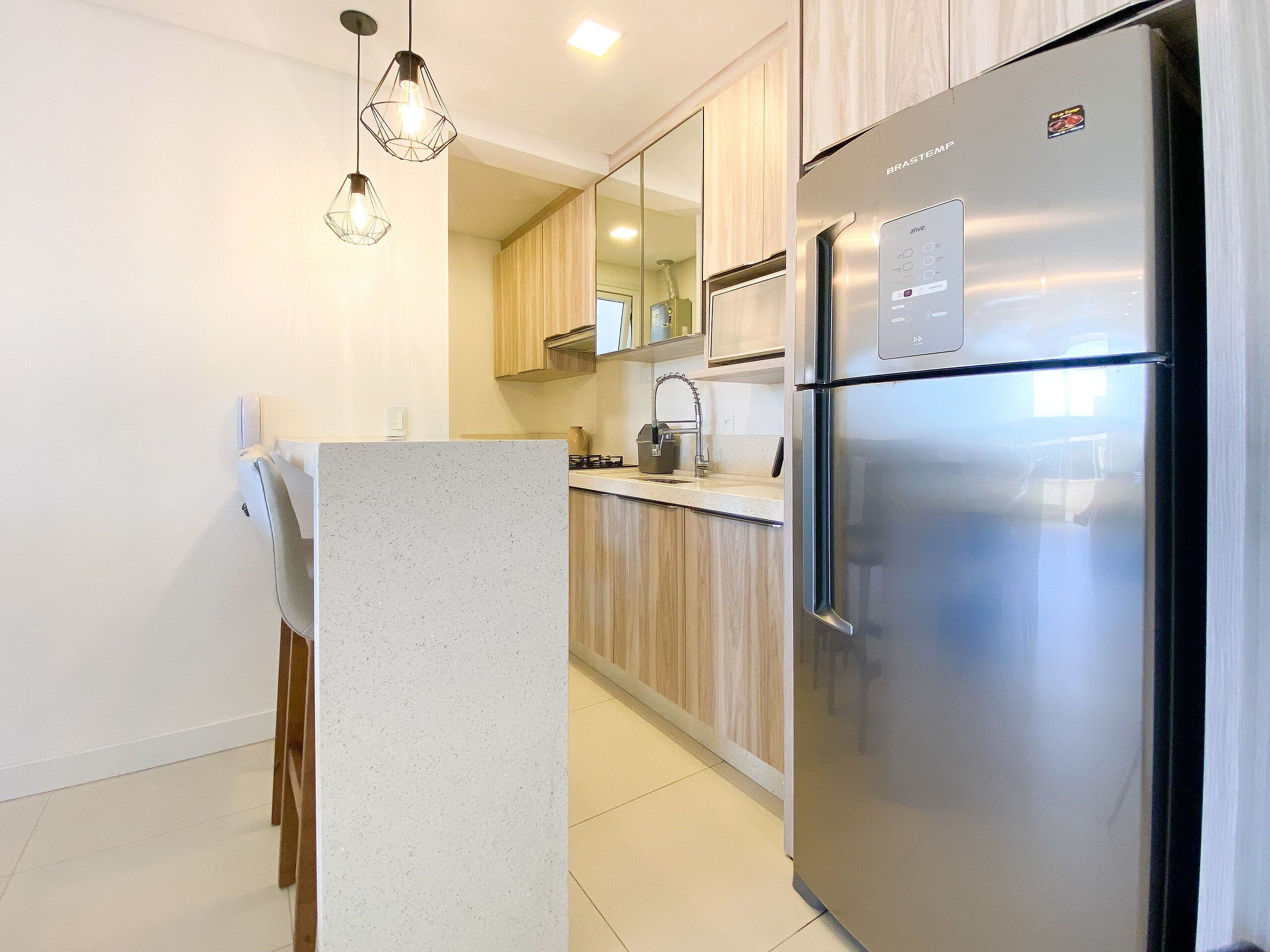 Una cucina moderna con frigorifero in acciaio inossidabile, mobili in legno e illuminazione a sospensione.