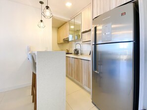 Una cocina moderna con refrigerador de acero inoxidable, armarios de madera e iluminación colgante.