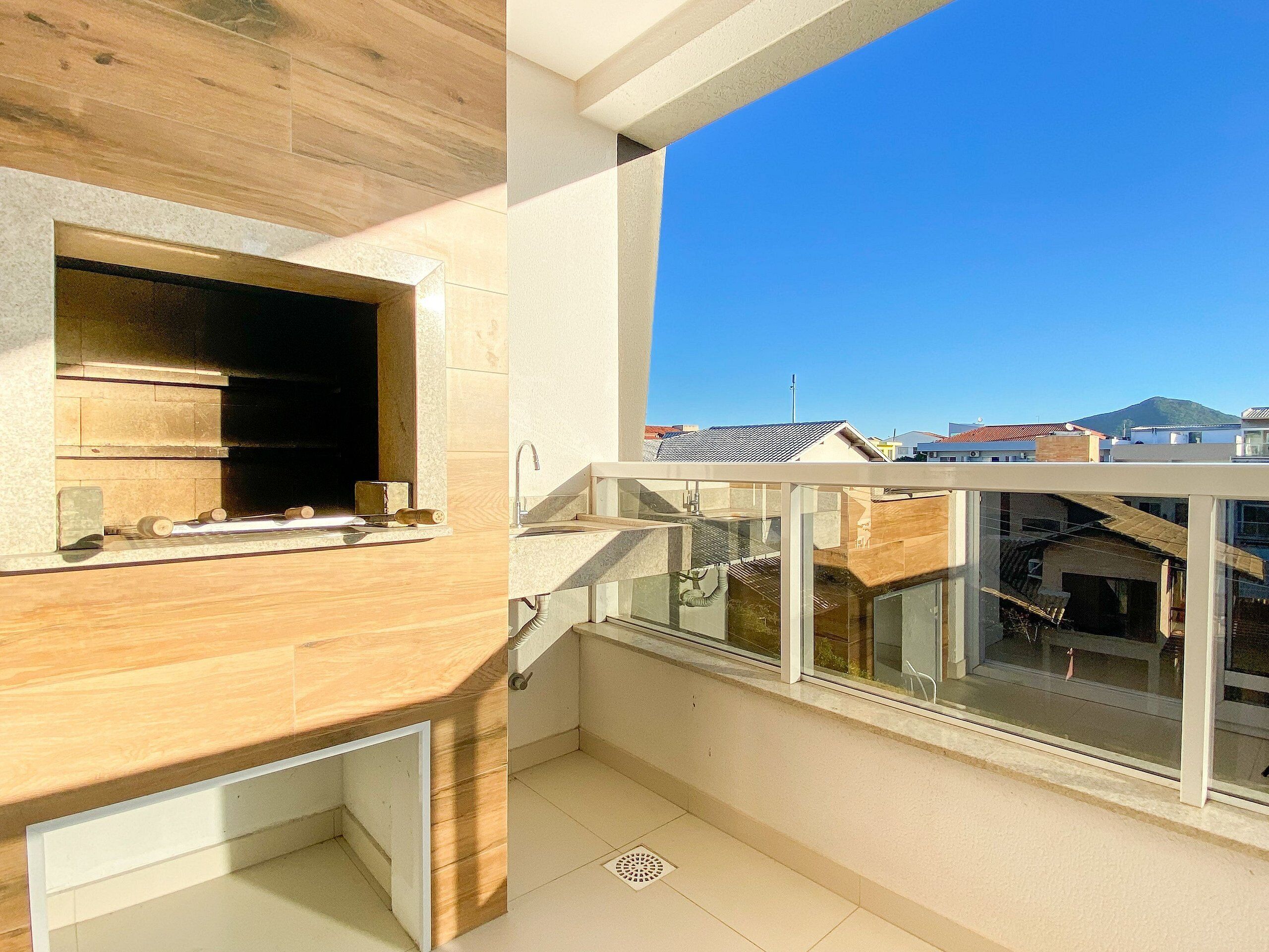 A balcony with a wooden countertop and a view of buildings and a mountain in the distance.