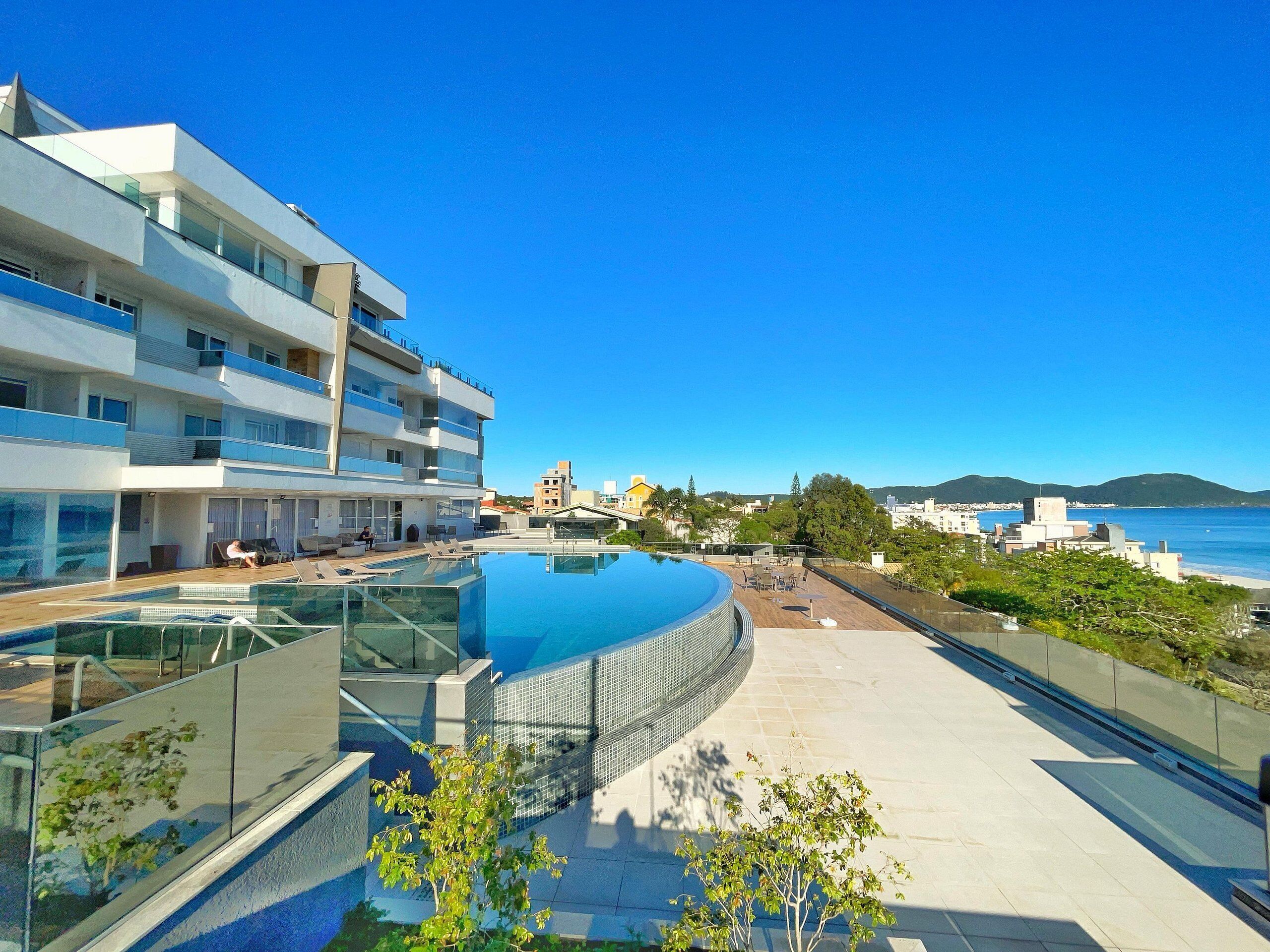 Ein modernes Hotel mit Dachpool und Panoramablick auf die Küstenlinie und die Hügellandschaft.
