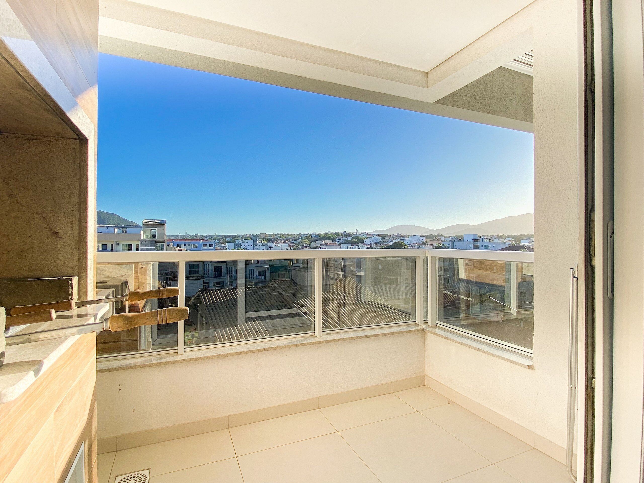 A balcony with a clear view of the cityscape, including buildings and distant hills.