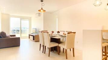 Una sala de estar moderna con comedor, que incluye un sofá, una mesa de comedor, sillas e iluminación colgante.
