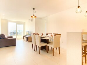 Una sala de estar moderna con comedor, que incluye un sofá, una mesa de comedor, sillas e iluminación colgante.