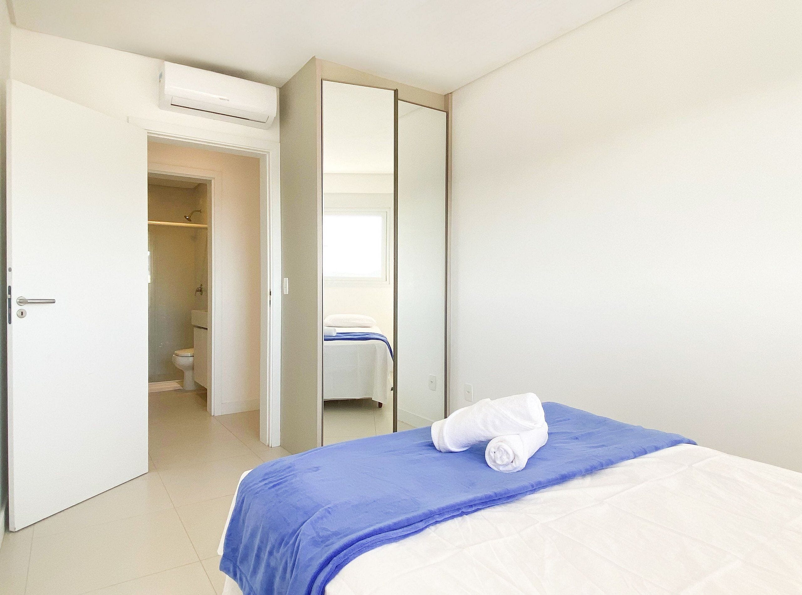 A hotel room with a bed, a bathroom, and a closet.