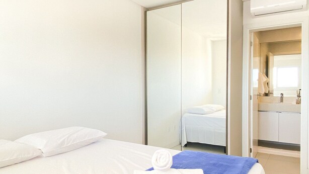 Ein Hotelzimmer mit einem Bett, einem blauen Handtuch und einer weißen Bettdecke.