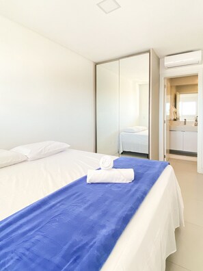 Una habitación de hotel con una cama, una toalla azul y una colcha blanca.