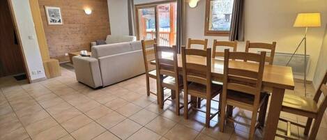 Un comedor con una mesa y sillas de madera, un sofá y un ventanal con cortinas.