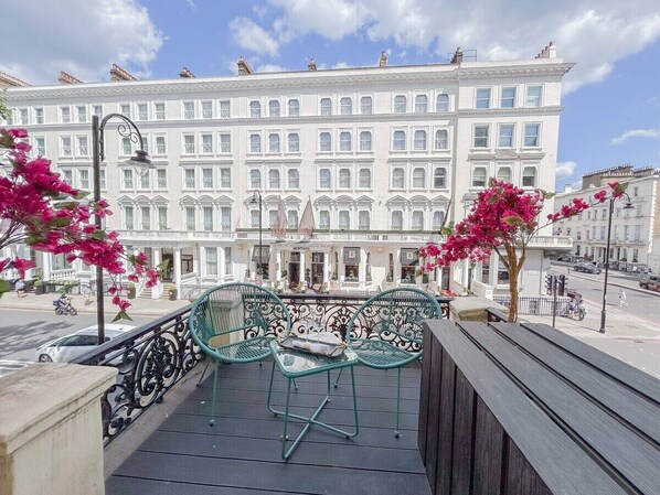 Enjoy the view from this balcony with a table and two chairs, overlooking a charming street scene.