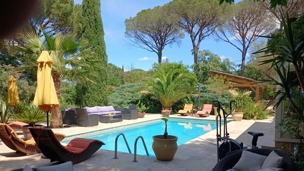 Ein Poolbereich mit Liegestühlen, einem kleinen Tisch und einer Pergola.