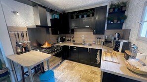 Eine moderne Küche mit dunklen Schränken, einer Holz Arbeitsplatte und einem blauen Mülleimer.