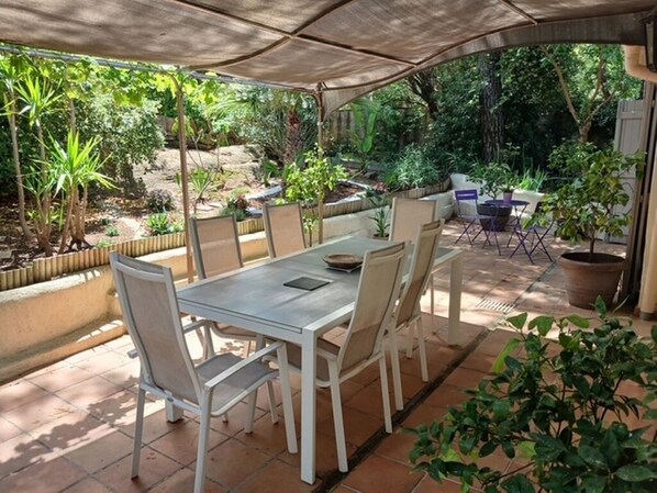 An outdoor patio with a table and chairs, surrounded by potted plants and a covered area. - Stunning villa with a pool, 3 bedrooms, 2 bathrooms, and a large living room... (Vidauban)