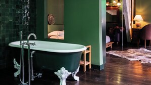 A room with a large bathtub, wooden flooring, and a green wall. - Verne Dreams (Ghent)