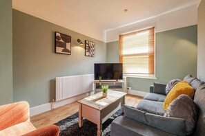 A living room with a sofa, a coffee table, a television, and artwork on the wall.