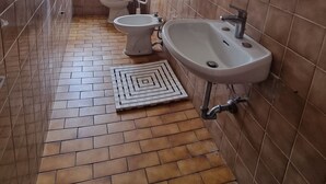 Un baño con inodoro, bidé, lavamanos y ducha.