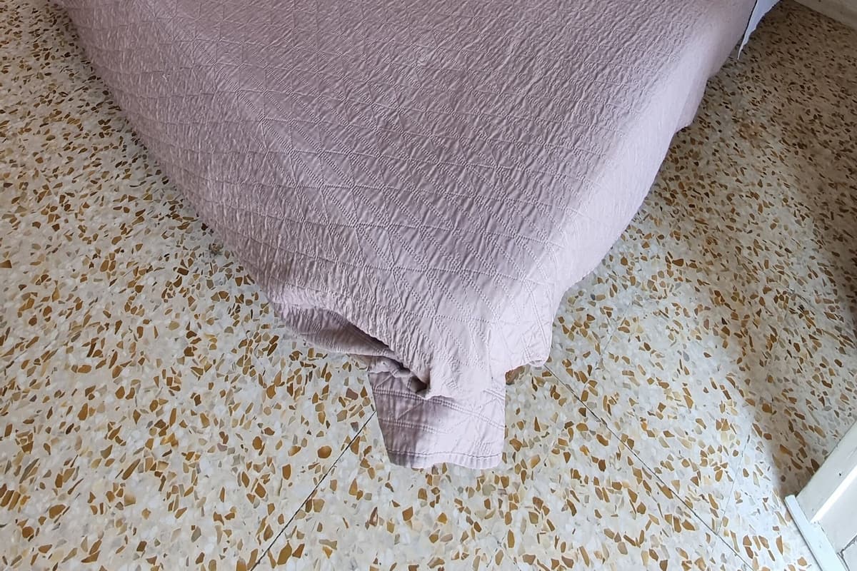 Ein Schlafzimmer mit einem Bett, einem Kleiderschrank, einem kleinen Tisch und einem Bild an der Wand.