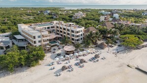 A resort with multiple buildings, a beach area with sun loungers, and palm trees. - Ana y Jose Holbox Boutique All Inclusive Hotel (Isla Holbox)