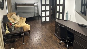 Et værelse med køjeseng, sofa, skrivebord og kommode.