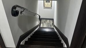 En trappe med gelænder i træ, en vægmonteret lampe og et billede med teksten "LOW HEADROOM".