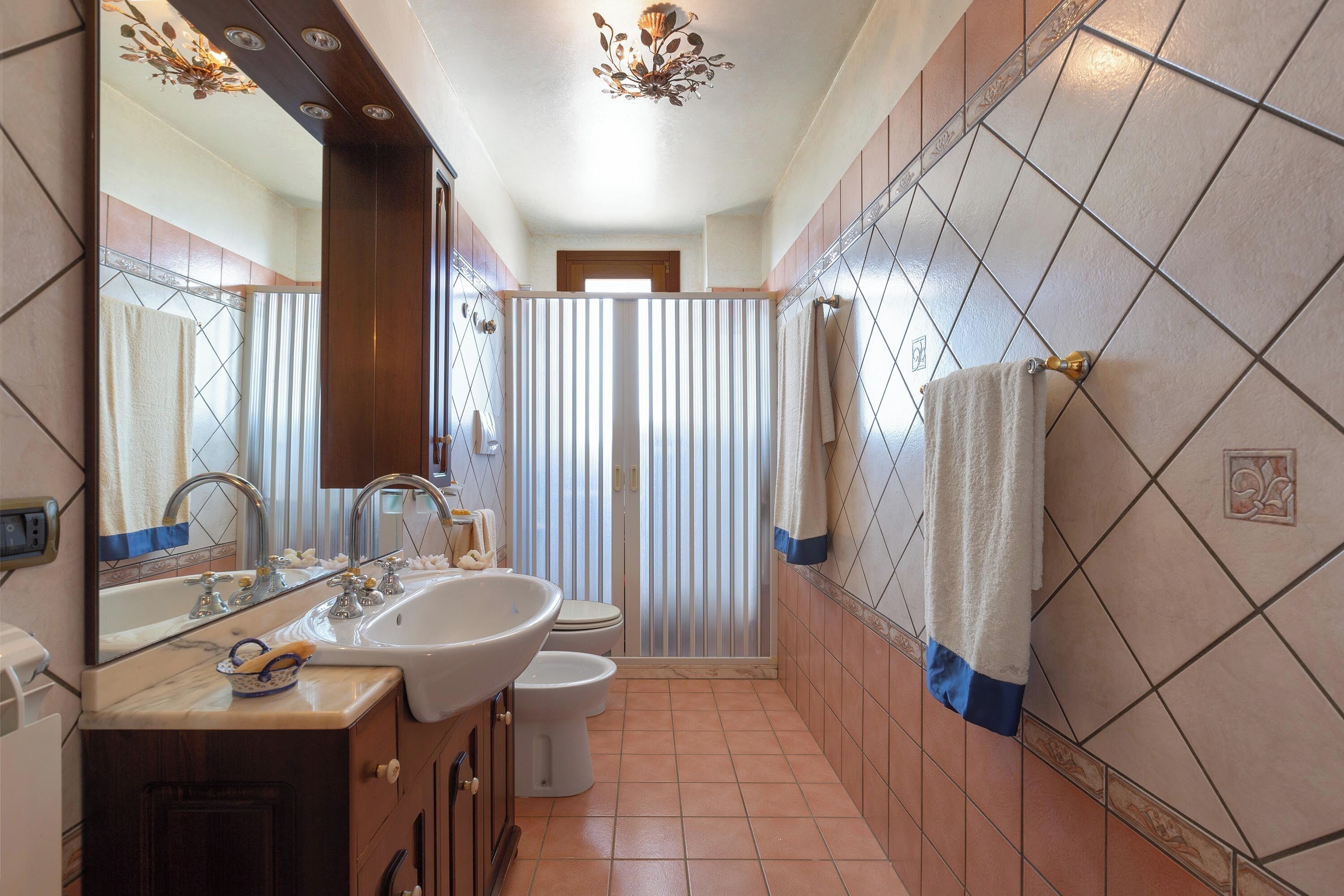 Een badkamer met een grote spiegel, een wastafel, toilet en een douchehoek.