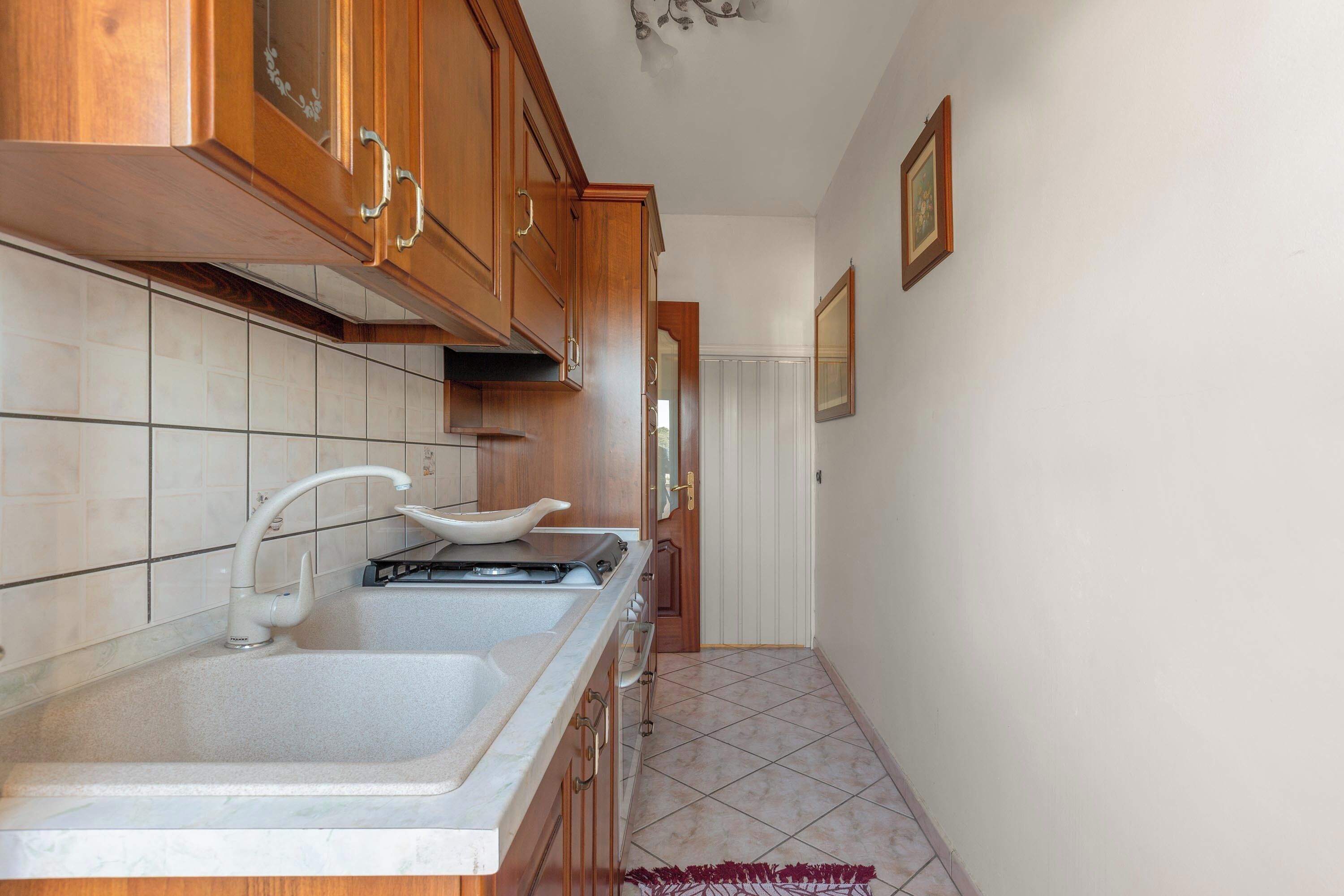 A kitchen with wooden cabinets, a double sink, and a stove.