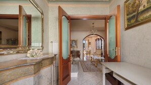 A hallway with a marble floor, a wooden door, a mirror, and a dining area with a chandelier. - Casa Pireddu by BarbarHouse (Castro)