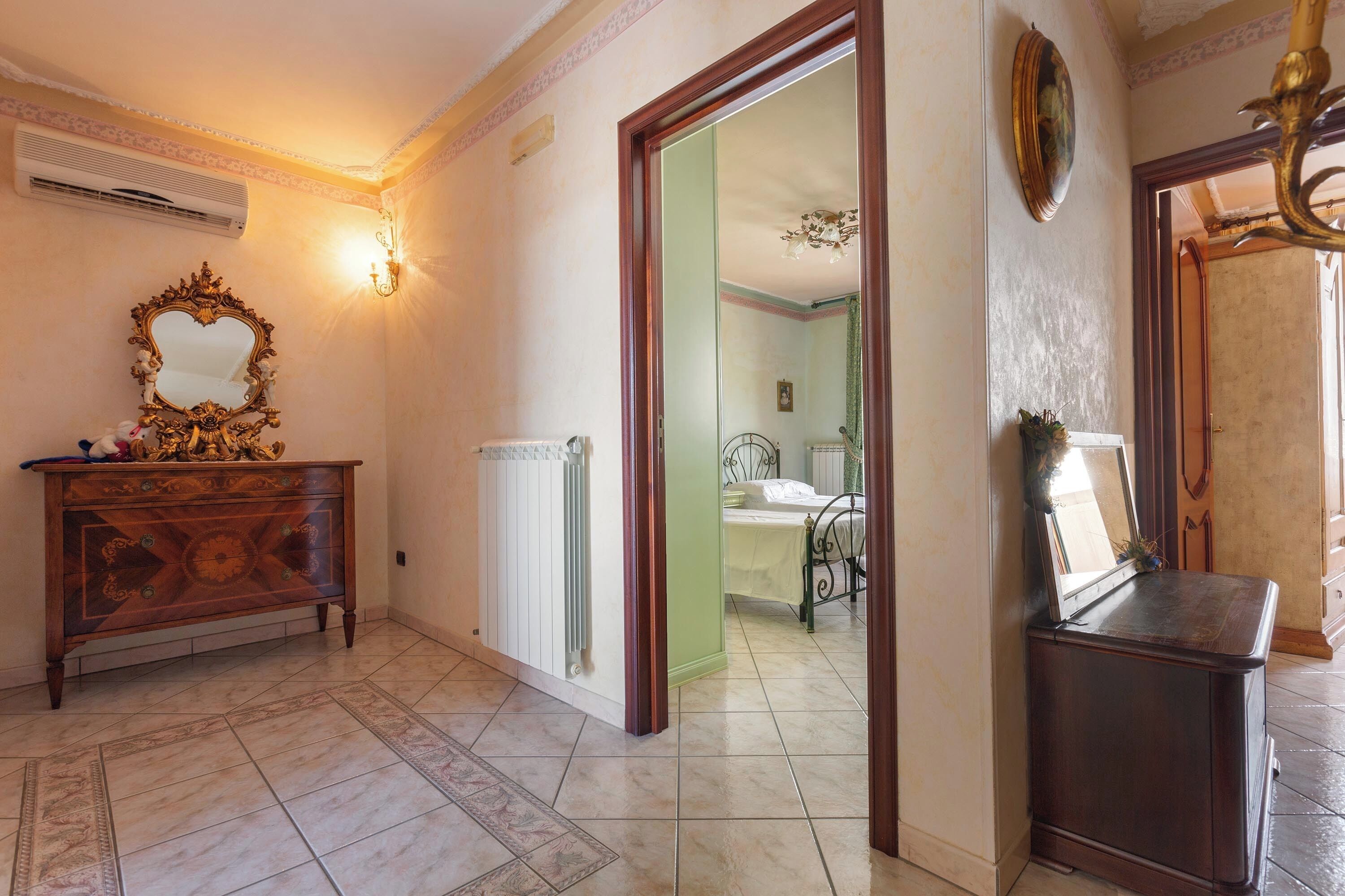 A hallway with a wooden dresser, a mirror, and a radiator.