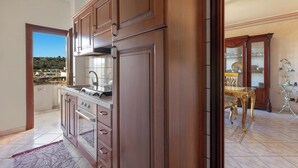A kitchen with wooden cabinets, a stainless steel sink, and a view of a hillside. - Casa Pireddu by BarbarHouse (Castro)