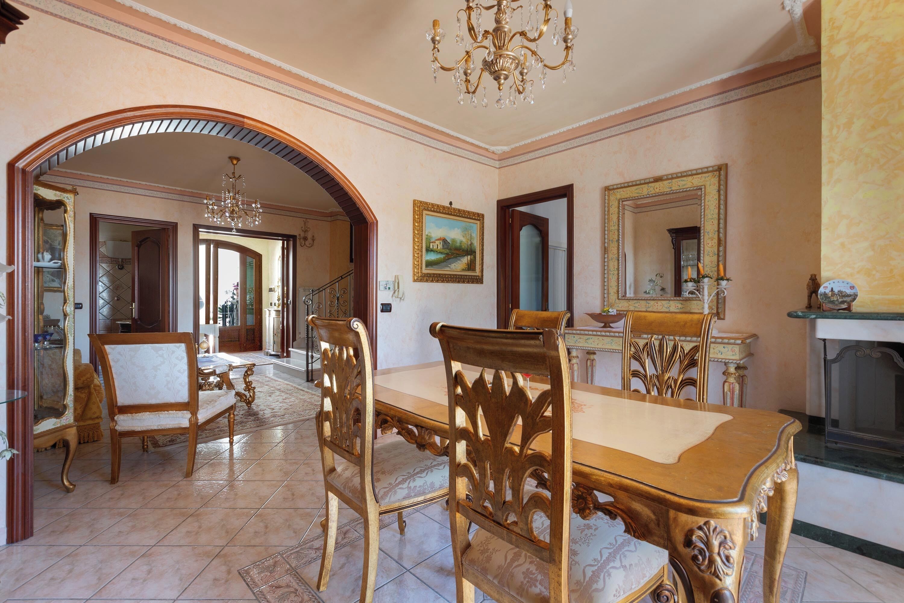 A dining area with a wooden table and chairs, a chandelier, and a fireplace.