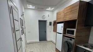 Een kleine keuken met een magnetron, oven en spoelbak.