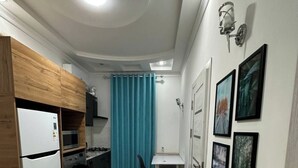 Een praktische keuken met moderne apparaten, een eethoek met een tafel en stoelen, en een gang met ingelijste foto's aan de muur.