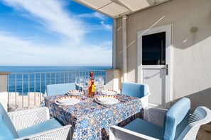 A balcony table set with plates, glasses, and a bottle, overlooking the sea. - Casa Ardito by BarbarHouse (Polignano a Mare)