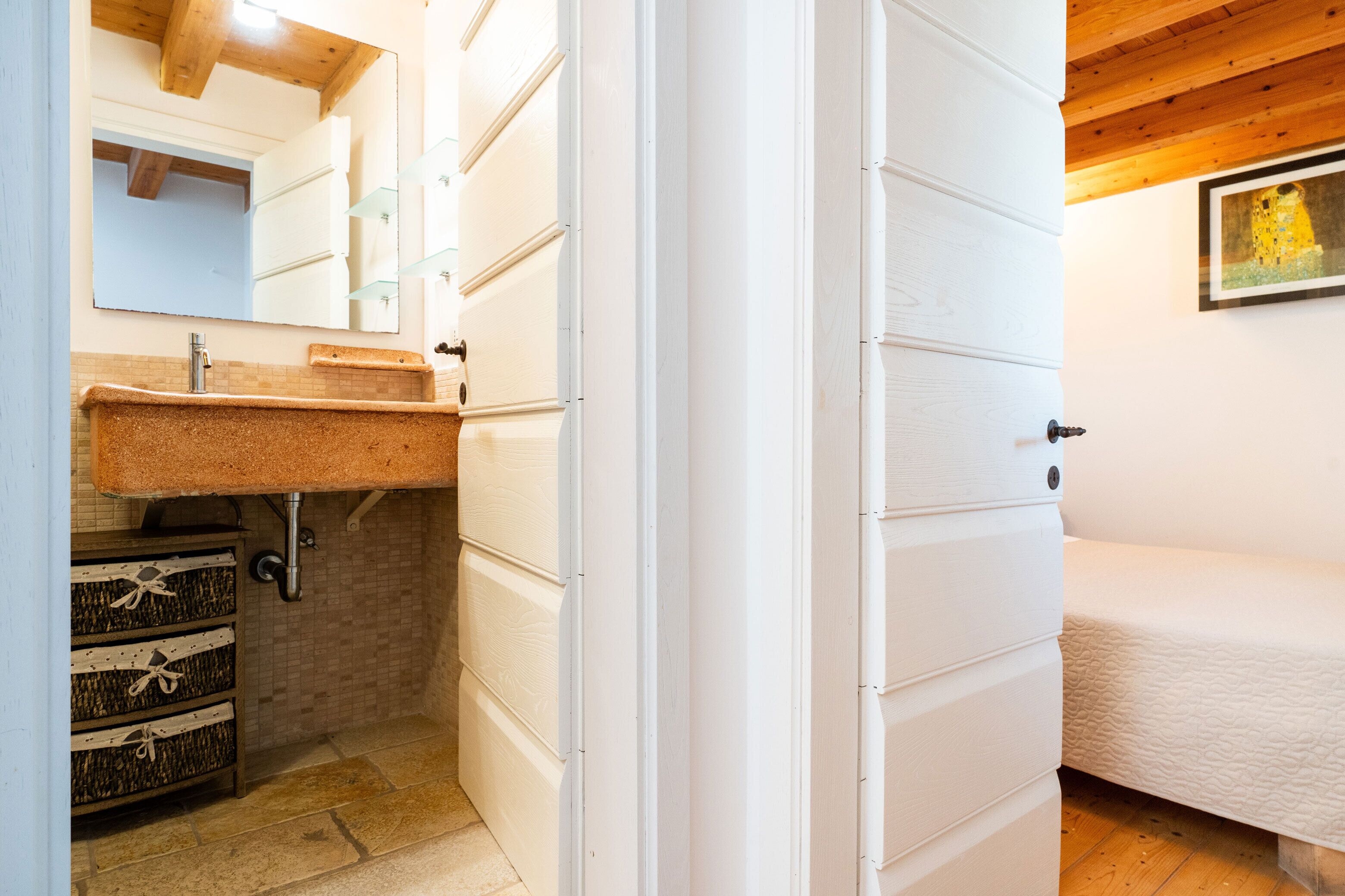 Un bagno con un mobile lavabo bianco, uno specchio e un armadietto in legno.