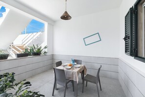 A corner dining area with a table set for four, surrounded by wicker chairs. - Villa Serenedad - Bilo PT by BarbarHouse (Torre Lapillo)