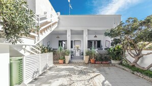 Un edificio moderno con facciata bianca, un cortile in pietra e piante in vaso.