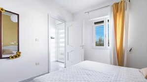 Una camera da letto con un letto, una finestra con tende, una porta e uno specchio con girasoli.