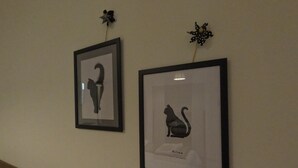 Deux silhouettes de chats encadrées sont accrochées au mur.