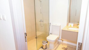Une salle de bain moderne dotée d’une douche à parois de verre, de toilettes et d’un lavabo.